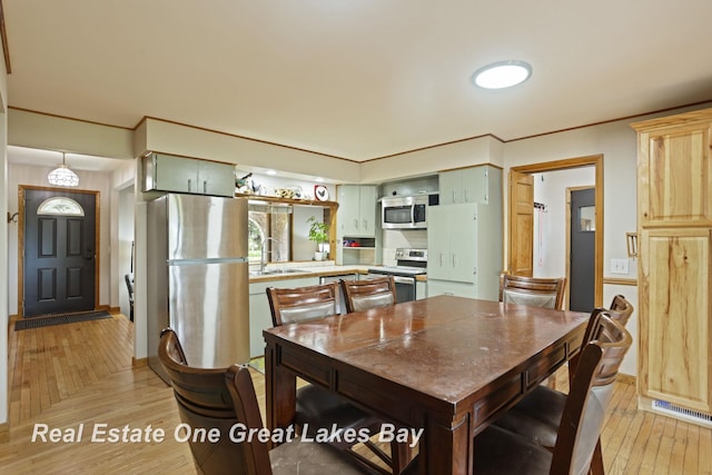 dining area with light wood finished floors, baseboards, and crown molding