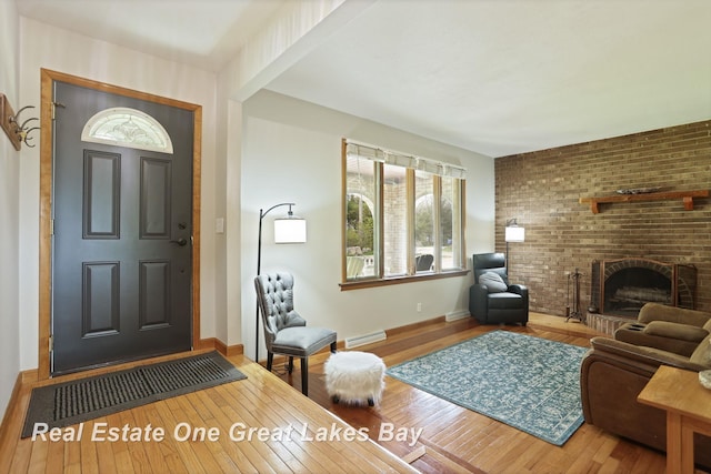 living room featuring hardwood / wood-style floors, a brick fireplace, and baseboards