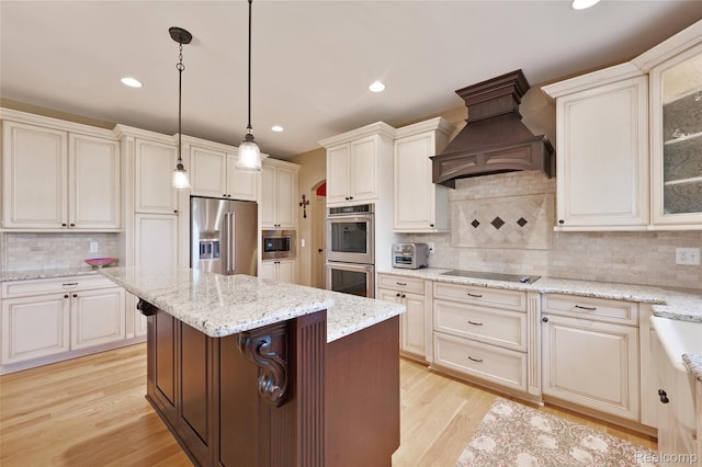 6100 30 Mile Rd, Washington, MI 48095 - kitchen with appliances with stainless steel finishes, custom range hood, tasteful backsplash, a center island, and light wood finished floors