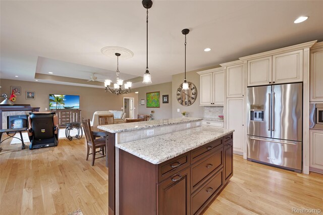 6100 30 Mile Rd, Washington, MI 48095 - kitchen featuring appliances with stainless steel finishes, light wood finished floors, cream cabinets, hanging light fixtures, and light stone counters