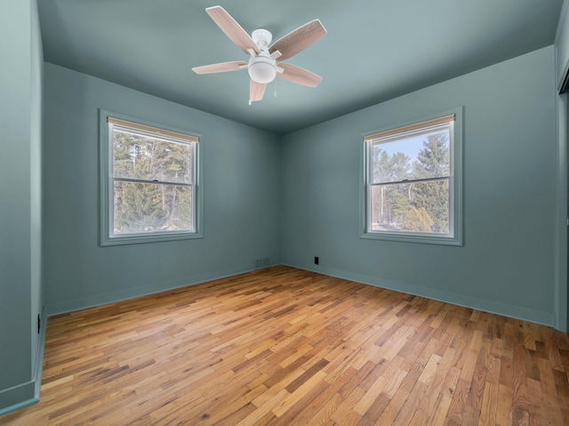 1330 N Orchard Dr, Traverse City, MI 49686 - empty room featuring plenty of natural light, light wood finished floors, a ceiling fan, and baseboards