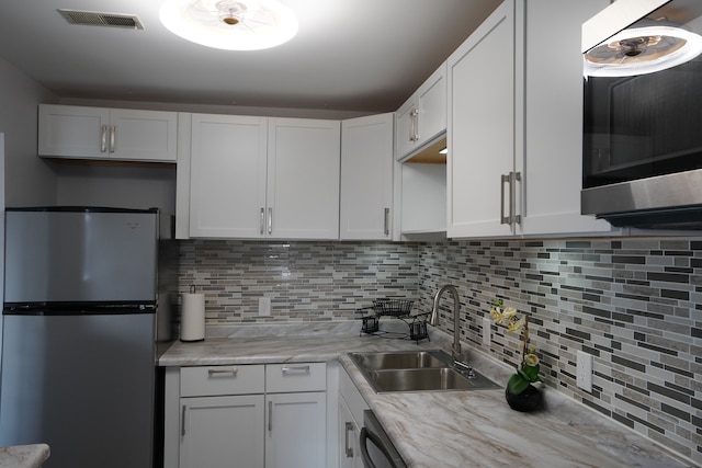kitchen featuring stainless steel appliances, a sink, light countertops, decorative backsplash, and white cabinets