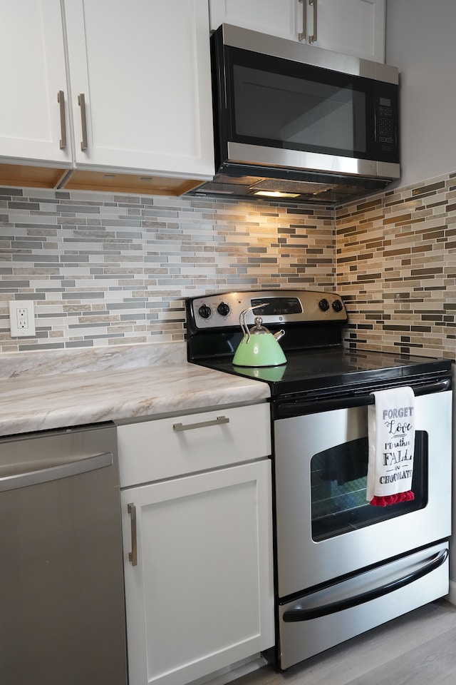 kitchen featuring appliances with stainless steel finishes, white cabinetry, and tasteful backsplash