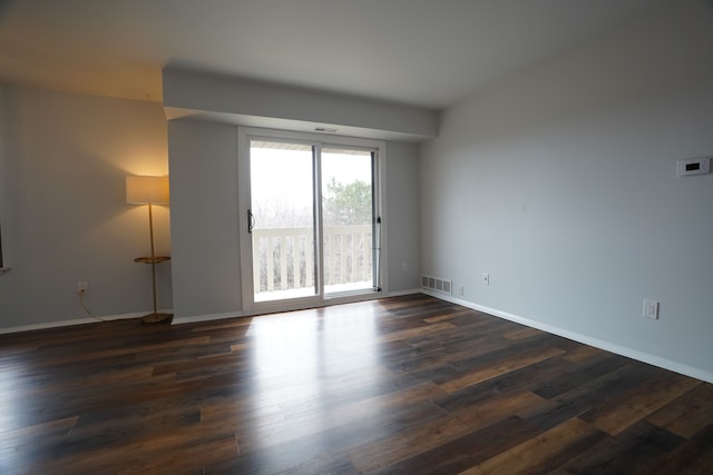 empty room featuring dark wood-type flooring and baseboards