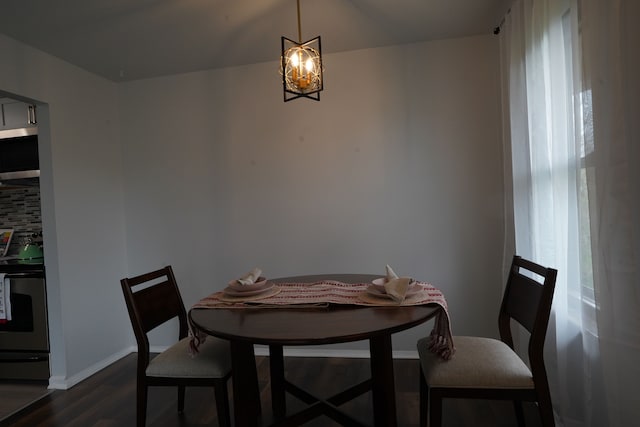 dining space with dark wood-style floors, a chandelier, and baseboards