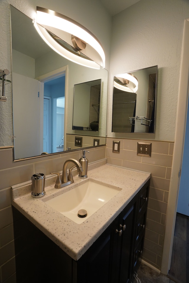 bathroom with tile walls, vanity, and a wainscoted wall
