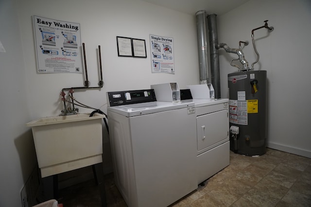 laundry area featuring gas water heater, a sink, washing machine and dryer, and baseboards