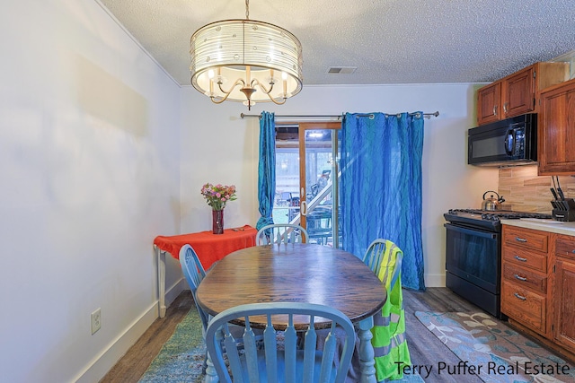 dining area featuring wood finished floors, a textured ceiling, a chandelier, and baseboards