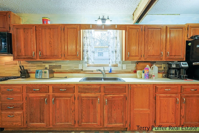kitchen with a sink, black microwave, a textured ceiling, light countertops, and decorative backsplash