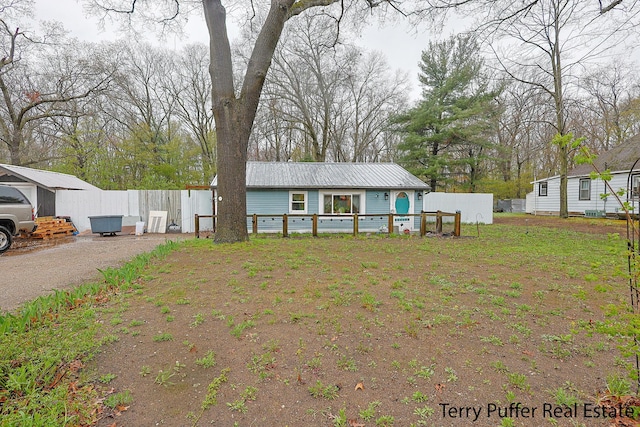 single story home featuring fence, metal roof, and dirt driveway