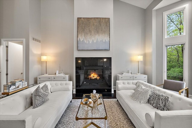 31080 Lucerne Dr, Franklin, MI 48025 - living room with high vaulted ceiling, healthy amount of natural light, a glass covered fireplace, and wood finished floors