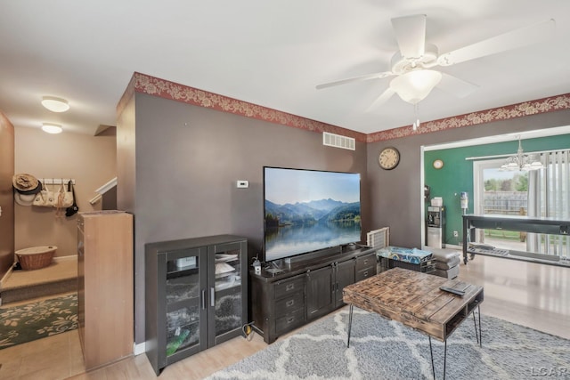 living room featuring ceiling fan, wood finished floors, and a chandelier