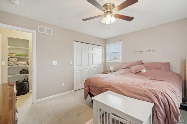 bedroom with a closet, light colored carpet, baseboards, and ceiling fan