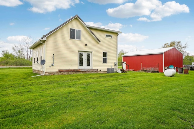 rear view of house featuring french doors, central AC, a yard, a pole building, and an outbuilding