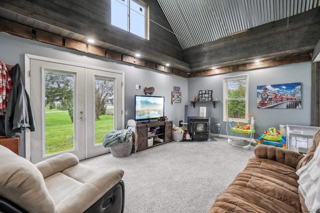 carpeted living room featuring french doors, a wood stove, high vaulted ceiling, healthy amount of natural light, and baseboards