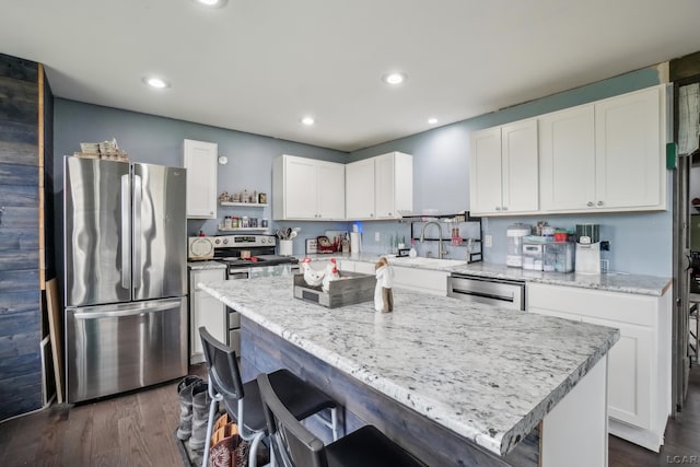 kitchen with appliances with stainless steel finishes, a sink, recessed lighting, white cabinetry, and a kitchen island