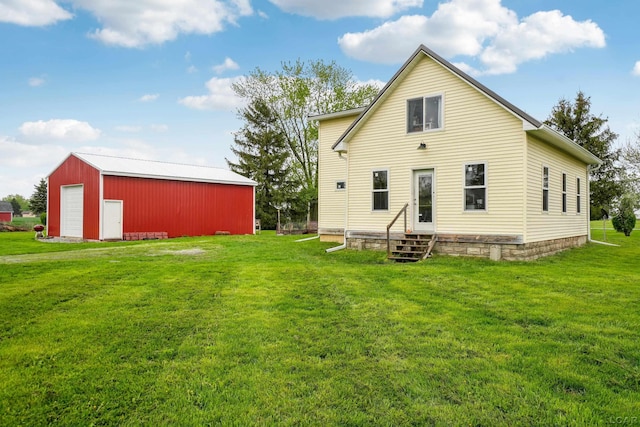 rear view of property with entry steps, a lawn, an outdoor structure, and a garage
