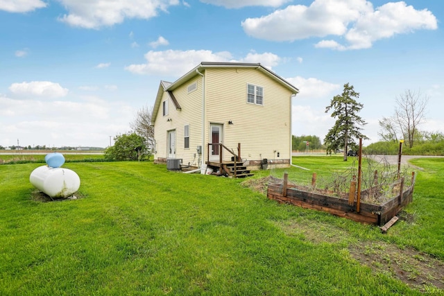 back of property with a garden, a yard, and central AC