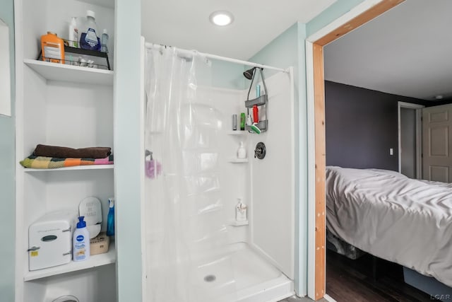 bathroom featuring ensuite bath, a shower stall, and wood finished floors