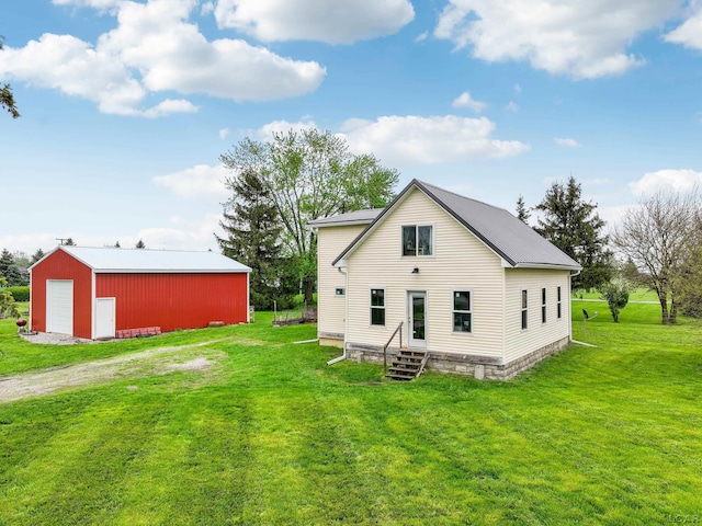 rear view of property featuring a garage, a yard, a pole building, an outdoor structure, and driveway