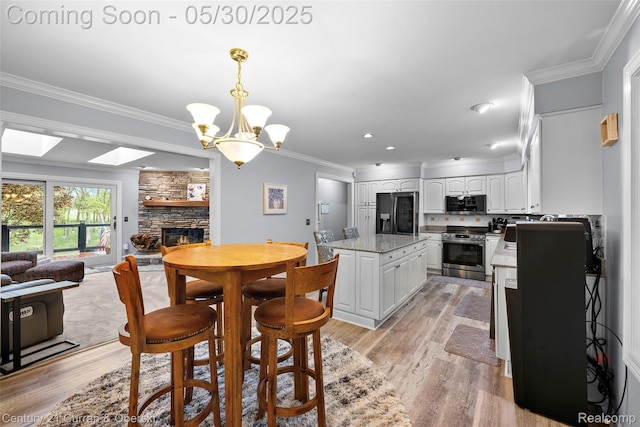 1162 Heights Rd, Lake Orion, MI 48362 - dining area featuring a stone fireplace, crown molding, light wood-style flooring, a chandelier, and recessed lighting