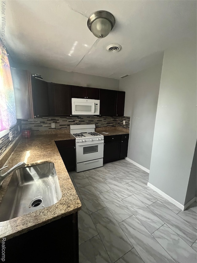 1714 Woodland St, Hamtramck, MI 48212 - kitchen with white appliances, light marble finish floors, backsplash, and dark cabinets