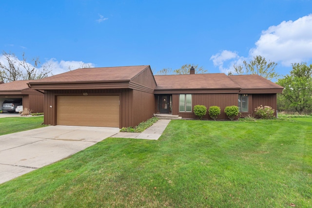 view of front of home with a garage, a chimney, concrete driveway, and a front lawn