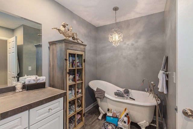 bathroom featuring wood finished floors, vanity, a soaking tub, and a chandelier