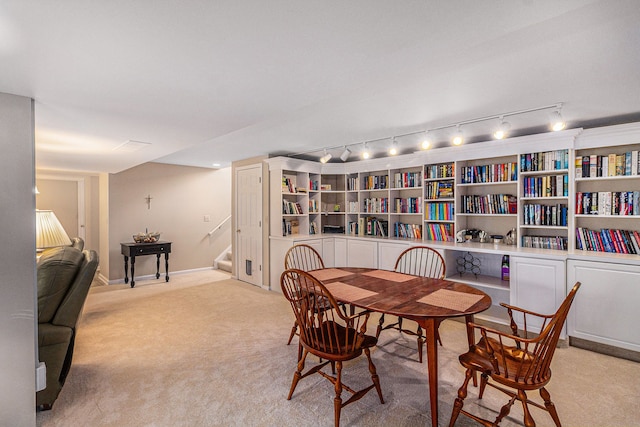carpeted dining space featuring stairs and rail lighting