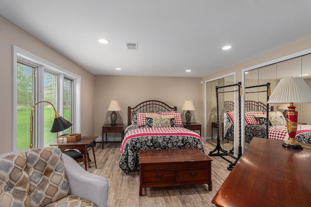 bedroom featuring light wood-style flooring, two closets, and recessed lighting