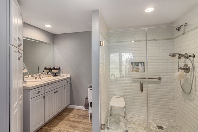 bathroom with a stall shower, vanity, wood finished floors, recessed lighting, and baseboards