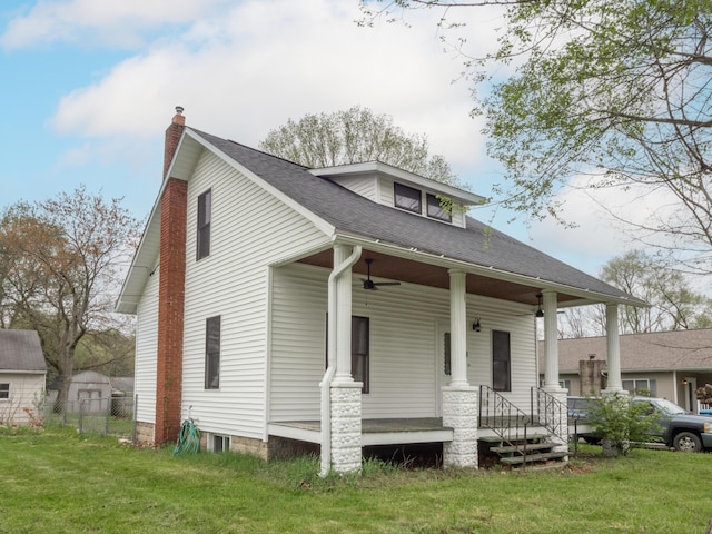 bungalow-style home with a chimney, covered porch, ceiling fan, and roof with shingles