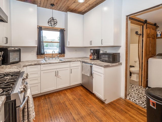 kitchen featuring a sink, stainless steel appliances, washer / dryer, white cabinets, and hardwood / wood-style floors
