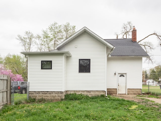 rear view of house with a chimney and roof with shingles
