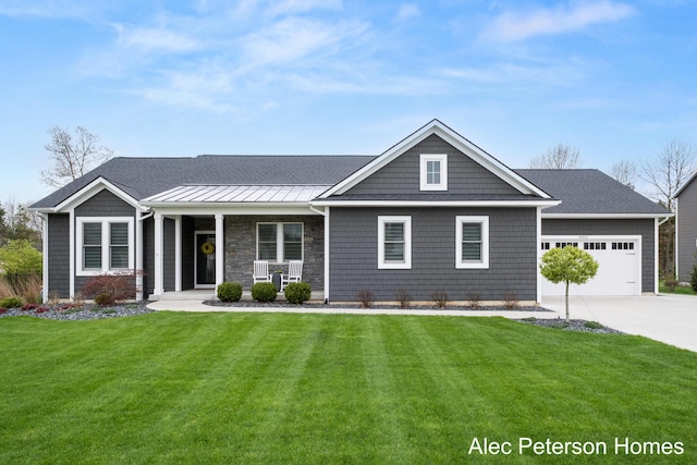 view of front of house with a porch, a front yard, concrete driveway, an attached garage, and a standing seam roof