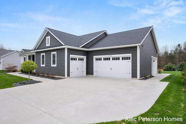view of front facade with an attached garage, concrete driveway, a front yard, and a shingled roof
