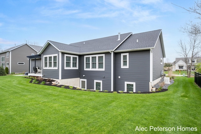back of house featuring a lawn, roof with shingles, and central air condition unit