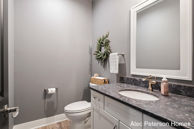half bathroom featuring toilet, vanity, and wood finished floors