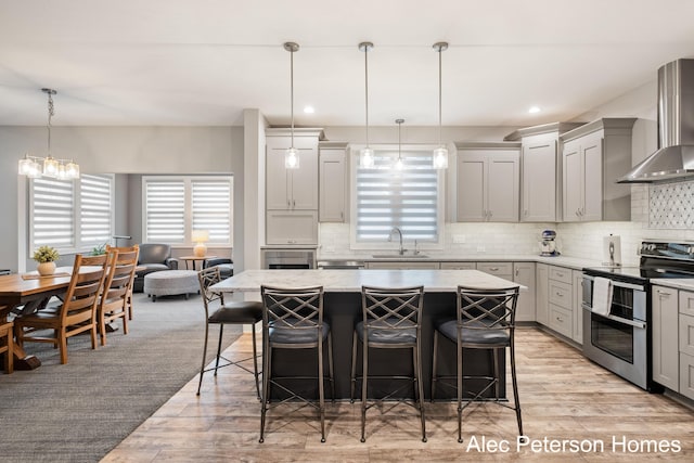 kitchen with double oven range, wall chimney range hood, a kitchen breakfast bar, light wood-type flooring, and recessed lighting