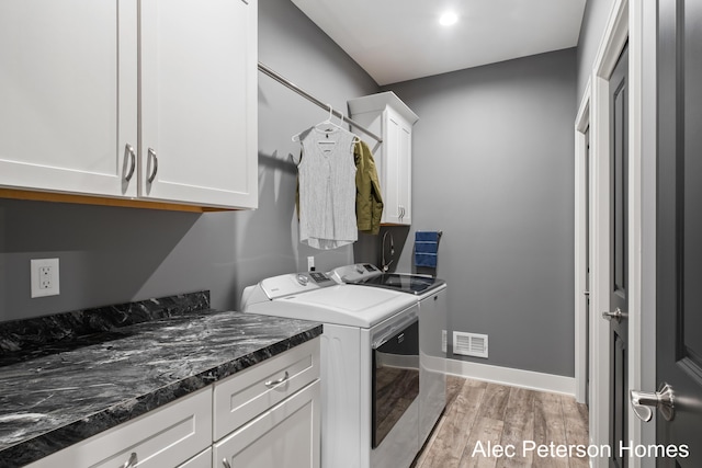 washroom featuring cabinet space, washer and dryer, light wood-type flooring, and baseboards