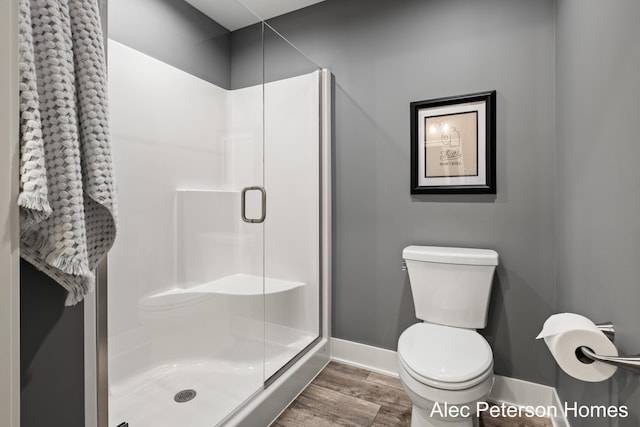 full bath with toilet, a shower stall, wood finished floors, and baseboards