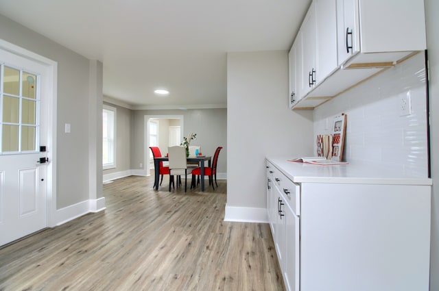 127 Bates St, Jackson, MI 49202 - kitchen featuring light wood-style flooring, baseboards, white cabinets, light countertops, and ornamental molding