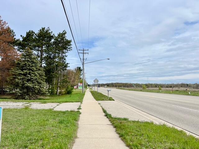 view of asphalt street featuring sidewalks, street lights, and traffic signs