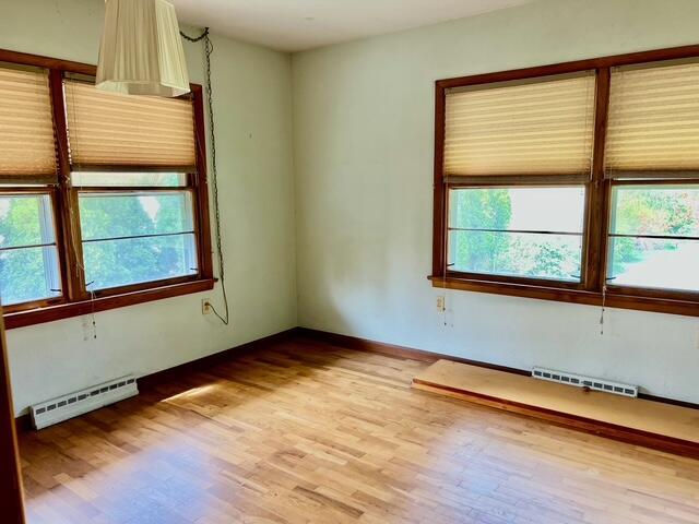 unfurnished room featuring baseboard heating, healthy amount of natural light, and light wood finished floors