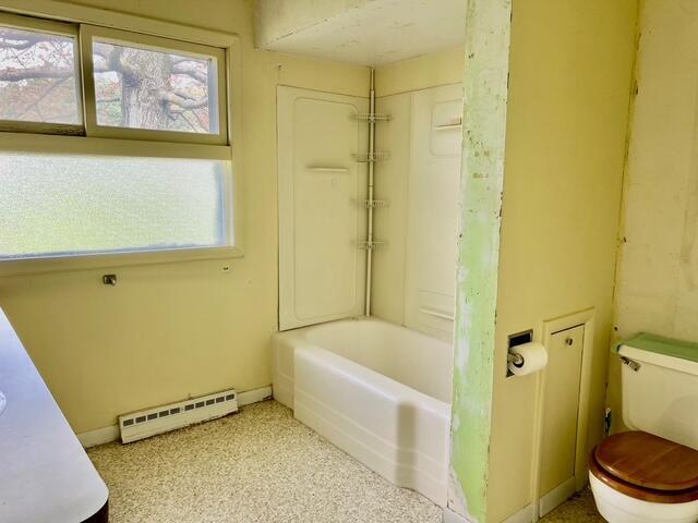 full bathroom featuring a baseboard heating unit, toilet, and shower / bath combo