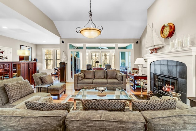 living room featuring lofted ceiling, a ceiling fan, a tile fireplace, and wood finished floors