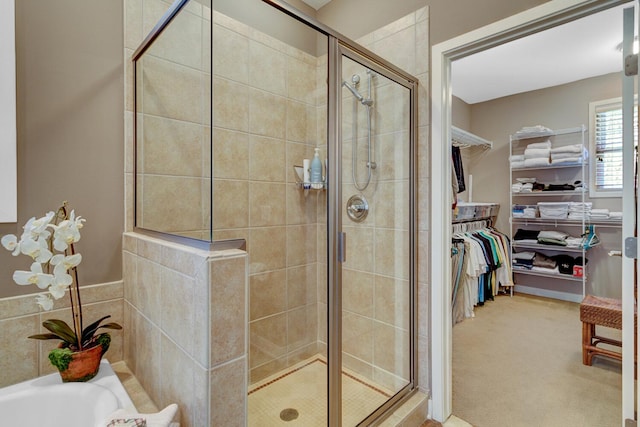 full bath featuring a shower stall, a spacious closet, and a bathtub