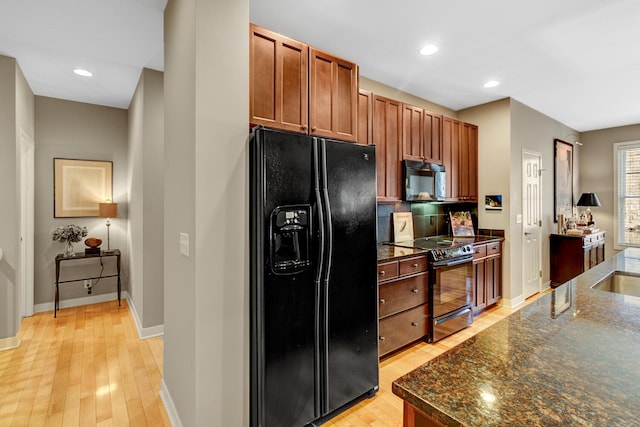 2700 Deep Forest Way, Fennville, MI 49408 - kitchen featuring black appliances, light wood-style floors, baseboards, dark stone counters, and brown cabinets