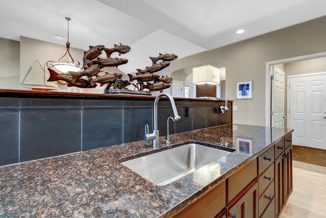 2700 Deep Forest Way, Fennville, MI 49408 - kitchen with a sink, dark stone counters, recessed lighting, brown cabinets, and arched walkways