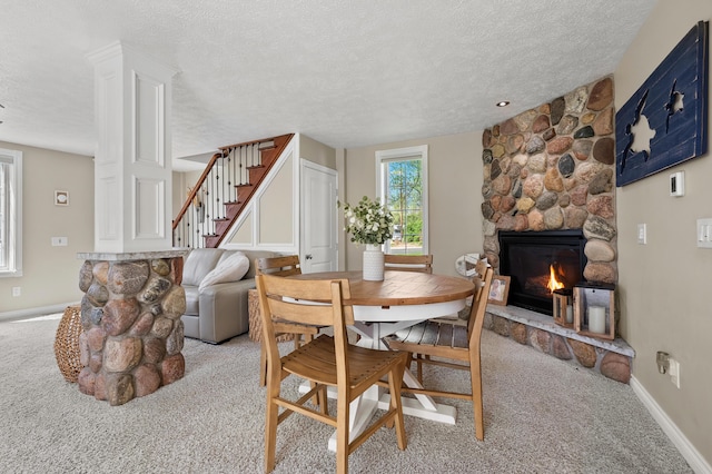 dining space featuring light carpet, stairway, a textured ceiling, and baseboards